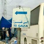a white bus parked next to a blue and white sign