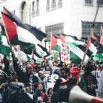 Protesters holding Palestinian flags in a demonstration outdoors, displaying unity and political activism.