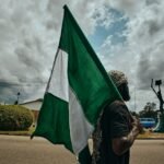 woman in black and white hijab holding green flag