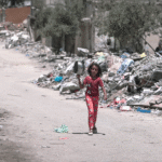 A_girl_walks_inside_Gaza_during_the_Gaza-Israel_war_to_get_food